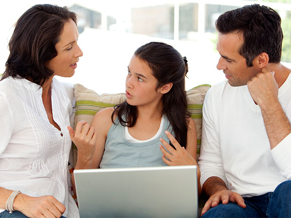 Photo of parents and their daughter looking at a laptop screen